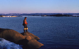 Photograph of an unidentified man fishing on the shore of Frobisher Bay