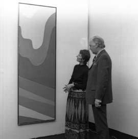 Photograph of two unidentified people with a painting