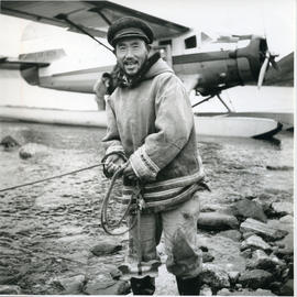 Photograph of Ningiok standing by an airplane at Wakeham Bay, Quebec