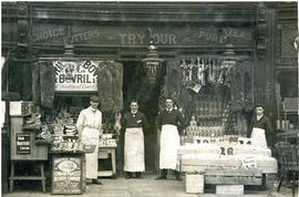 Photograph of four men, including T.H. Raddall, Sr., wearing aprons outside a grocery store