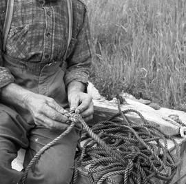 Photograph of an unidentified man working with a rope
