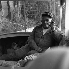 Photograph of a man in coveralls smoking a cigar