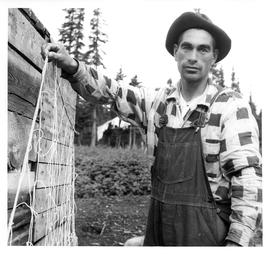 Photograph of an unidentified man wearing a plaid shirt and holding a seal net