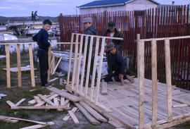 Photograph of four boys building a small house together