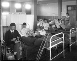 [Convalescing soldiers sewing, embroidering, weaving in bed and a wheelchair with nurse watching ...