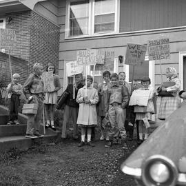 Photograph of children holding signs about a bus