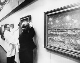 Photograph of unidentified man and Evelyn Holmes installing a painting