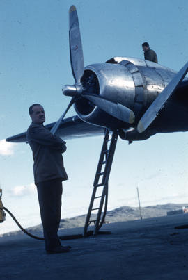 Photograph of Clare Dobbin standing by a plane in Frobisher Bay, Northwest Territories