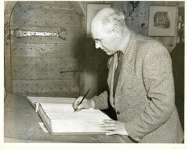 Photograph of Thomas Head Raddall signing the register of the Habitation at Lower Granville after...