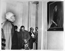 Photograph of an unidentified person looking at a portrait