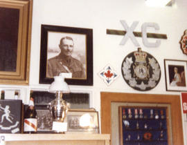 Photograph of a museum display of Royal Winnipeg Rifles Regiment artifacts including a portrait o...