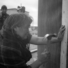 Photograph of Alicie Berthé hammering a nail into her house in Fort Chimo, Quebec