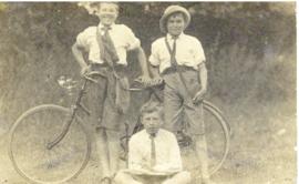 Portrait of George Smith, Eric Wallingford, and Cyril Smith with a bicycle printed on a postcard