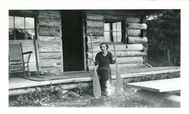 Photograph of Edith Raddall sitting on a porch and holding two oars