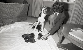 Photograph of an unidentified person with a dog and puppies at Howe Hall