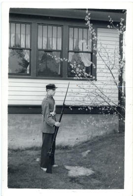Photograph of Arthur White standing in profile, dressed in period uniform, and holding a rifle an...