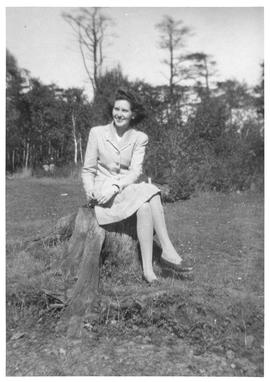 Photograph of an unidentified person sitting on a tree stump