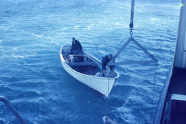 Photograph of two men and a small boat collecting mail in Emily Harbour, Newfoundland and Labrador