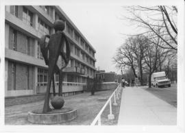 Photograph of a sculpture called "20th Century Student" in front of the Student Union Building