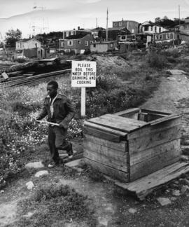 Photograph of a person walking by a well in Africville