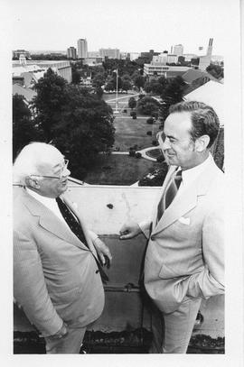 Photograph of Henry Hicks and an unidentified person standing on the roof of the Henry Hicks Acad...