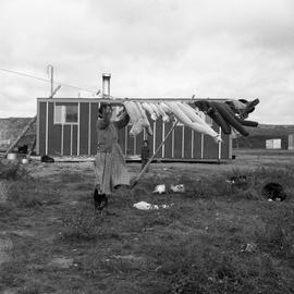 Photograph of a woman hanging laundry on a clothesline in Fort Chimo, Quebec