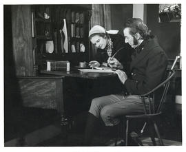 Photograph of a woman in contemporary dress conferring with actor David Murray, in period costume...