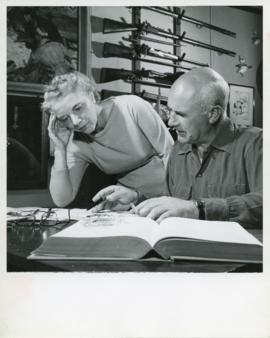 Photograph of Edith and Thomas Head Raddall smoking and editing a typed manuscript together in Ra...
