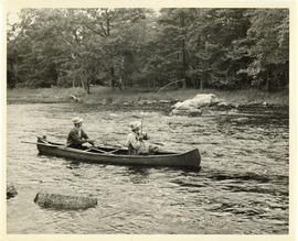 Photograph of two men reeling a fish and prepping a net from a canoe on Mersey River near Maitlan...
