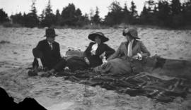 Two women and a man sitting on a beach