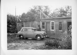 Photograph of a car and two sheds