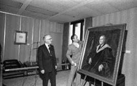 Photograph of Chester Stewart looking at a painting of himself
