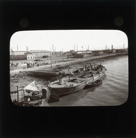 Photograph of a boat next to unidentified buildings