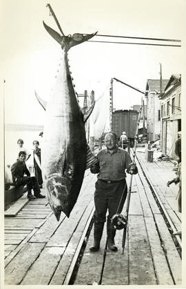 Photograph of an unidentified man with his tuna catch