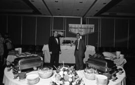Photograph of two unidentified people with a buffet