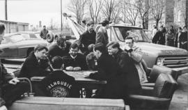 Photograph of students playing cards outside the Student Union Building, blocking a tow truck dri...
