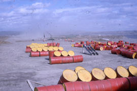 Photograph of several red barrels in a dust storm