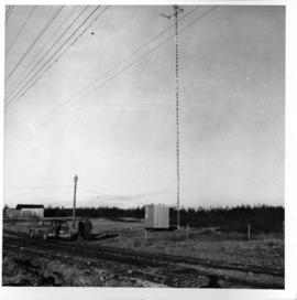 Photograph of an unidentified radio tower with two people on the ground