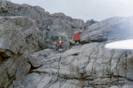 Photograph of two people standing on a rock formation in the eastern Canadian Arctic