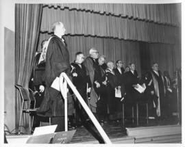 Photograph of unidentified people and Dr. A. E. Kerr in robes on stage