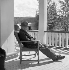 Photograph of John Drabson sitting on the verandah of the Old Men's Home in Dawson City, Yukon