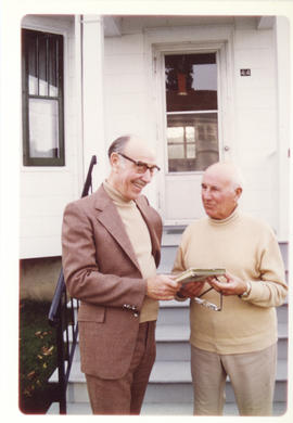 Photograph of former radio operator Reverend Harry Meadows looking at a book with Thomas Head Rad...