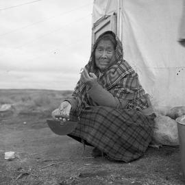 Photograph of Alacee Qingalik holding an ulu and a cigarette in Povungnituk, Quebec