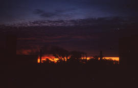 Photograph of houses and trees silhouetted against a sunset