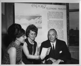 Photograph of three people examining a brochure at the 1967 World Exhibition in Montreal