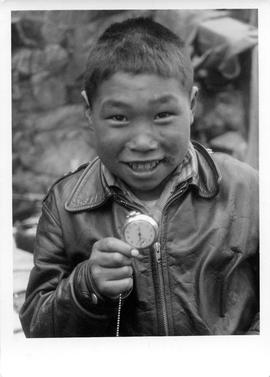 Photograph of a boy named Sapinak holding a pocket watch
