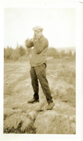 Photograph of a man holding a rifle and pretending to shoot the camera