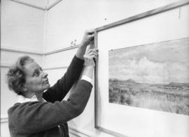Photograph of Evelyn Holmes hanging a picture