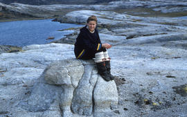 Photograph of Barbara Hinds sitting on a rock near Cape Dorset, Northwest Territories