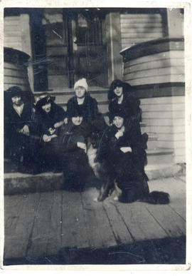 Photograph of a group of women wearing hats and posing with a dog